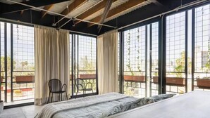 A bedroom with a bed, two chairs, large windows, and a view of the outdoors. - Argentina by Pardela (Guadalajara)