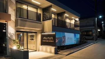Un hotel boutique moderno con una entrada llamativa, ventanas amplias y una fachada bien iluminada.