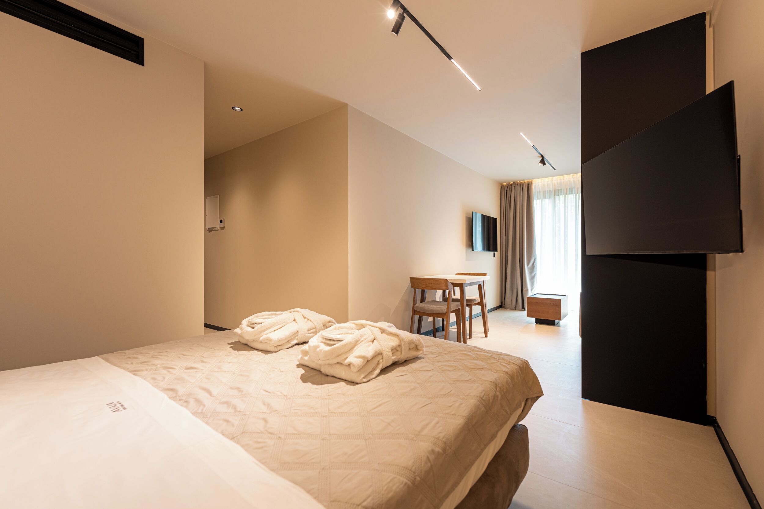 Een hotelkamer met een bed, een bureau, een stoel, een flatscreen televisie en een kledingkast.