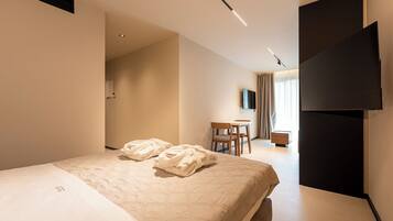 Een hotelkamer met een bed, een bureau, een stoel, een flatscreen televisie en een kledingkast.