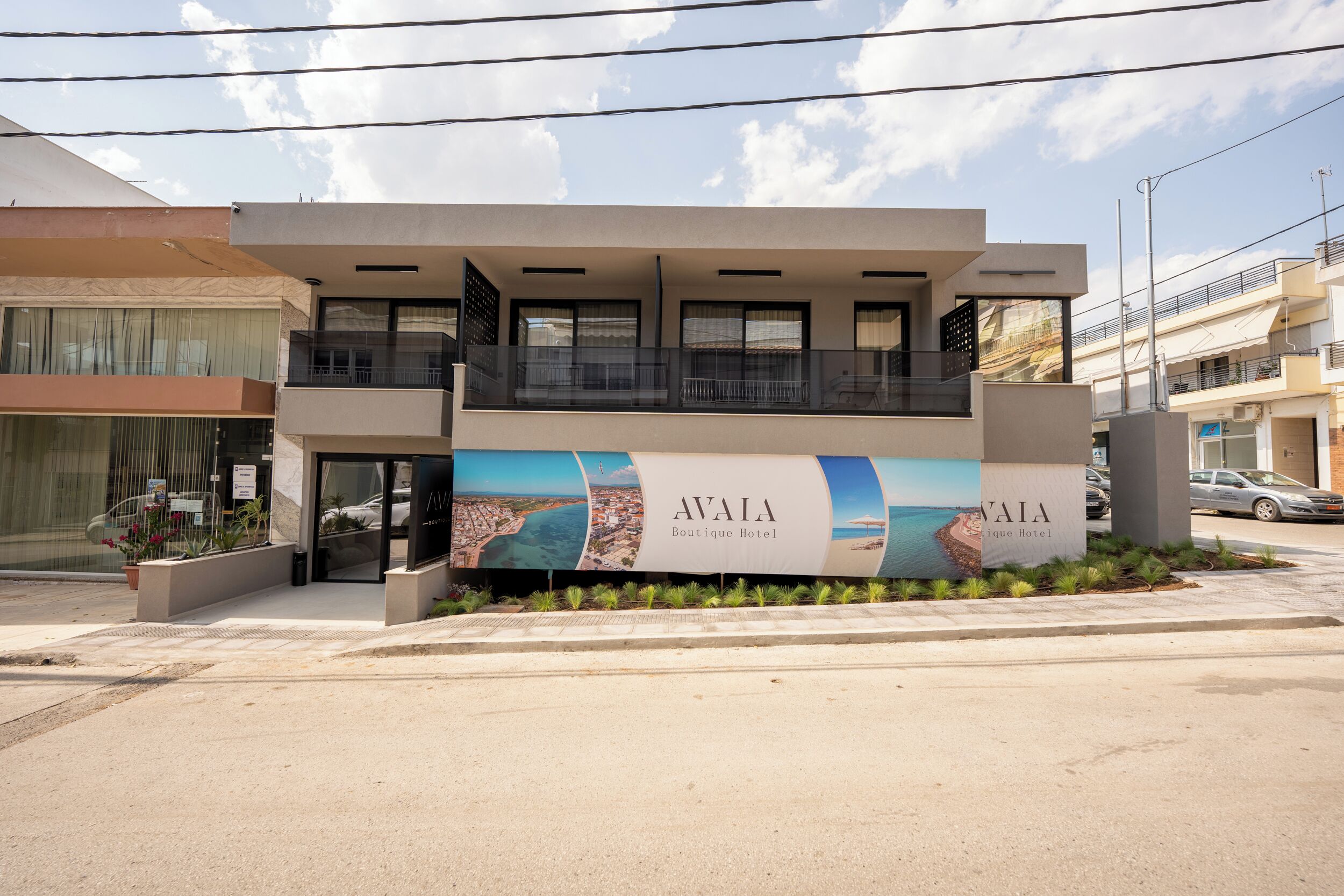 A modern hotel with a prominent sign, a balcony, and a view of the sea.