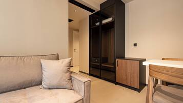 A modern living room with a sofa, a wooden dining table, and a built-in wardrobe.