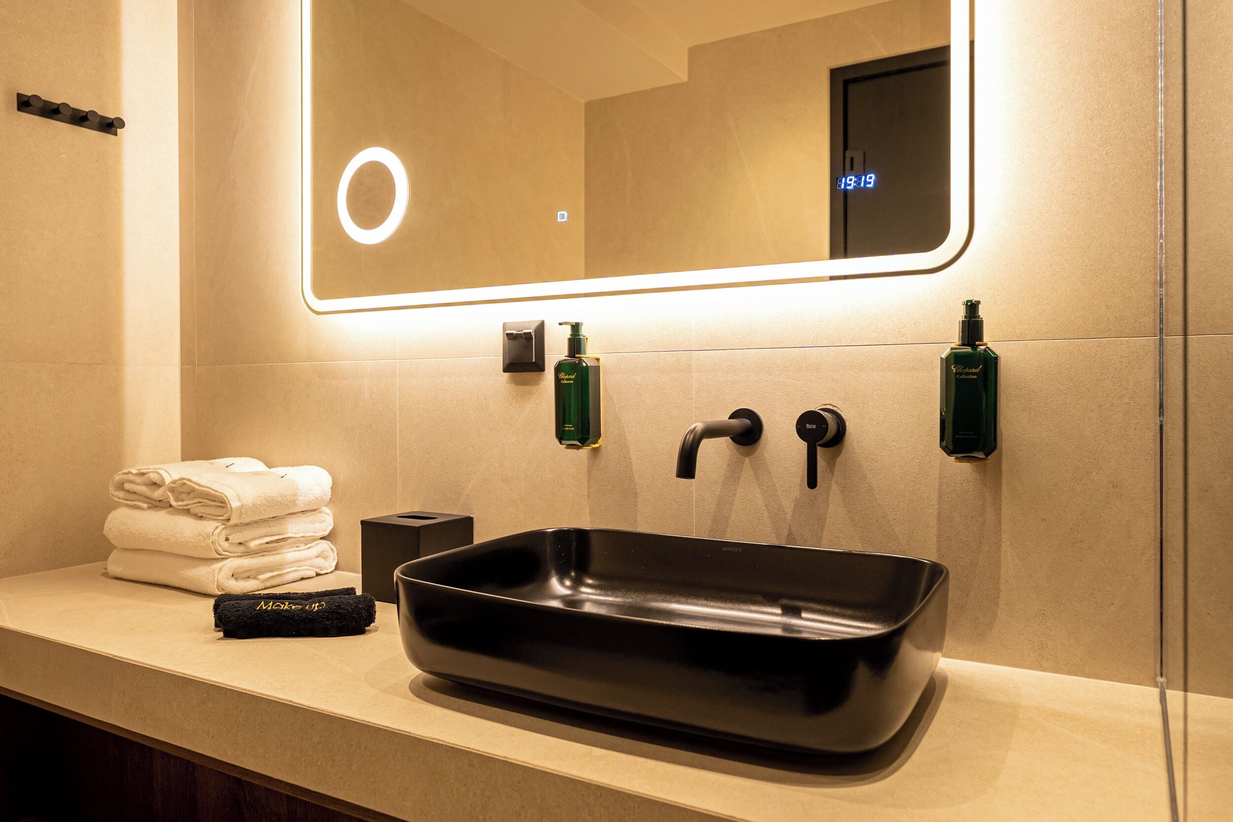 A bathroom with a black sink, a mirror, and a towel rack with folded towels.