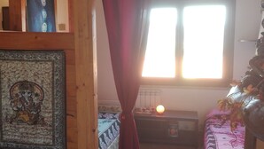 Una habitación con cama, ventana, radiador y cortina.