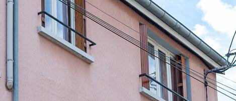 Un edificio rosa con varias ventanas, un balcón y una puerta de garaje.