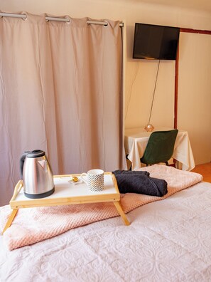 Ein Schlafzimmer mit Bett, Nachttisch, Fernseher und Vorhang.