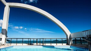 A swimming pool with a clear view of the sea and mountains in the background. - SHB Apartamento Com Vista ao Mar (Santos)