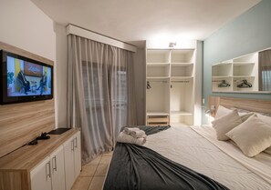 Ein Hotelzimmer mit Bett, Fernseher, Kleiderschrank und Spiegel.