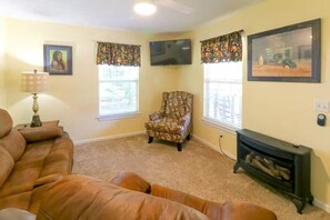 A living room with a sofa, a patterned armchair, a television, and a fireplace. - The Big Bear Retreat in Helen (Helen)