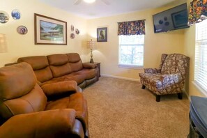 A living room with a brown leather sofa, a patterned armchair, a flat-screen TV, and a fireplace. - The Big Bear Retreat in Helen (Helen)