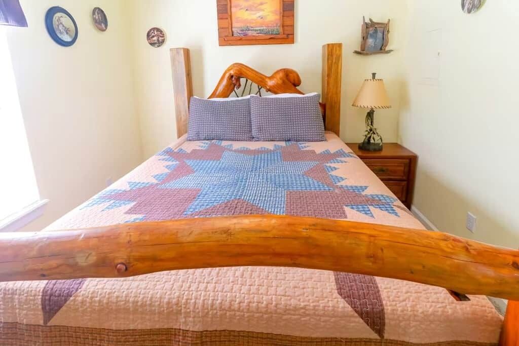 Un lit avec une tête de lit en bois, une couvre-lit à motifs et une table de chevet avec une lampe.