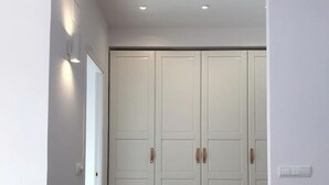 Un couloir avec un plancher en bois, une porte blanche et un placard à deux portes.