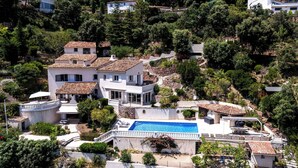 Uma villa numa encosta com piscina, jardim em terraços e vários edifícios.