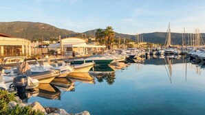 A marina with boats docked, a building with a sign, and mountains in the background. - CASA-Fontaine Luxury Villa in Gigaro (Cavalaire-sur-Mer)