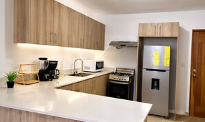 Eine moderne Küche mit Holzausstattung, einem Edelstahlkühlschrank, einem Herd, einer Mikrowelle und einer Kaffeemaschine.