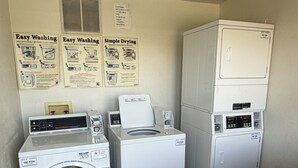 Een wasserette met een voorlader wasmachine, een droger met bovenlader en een gestapelde was-droogcombinatie.