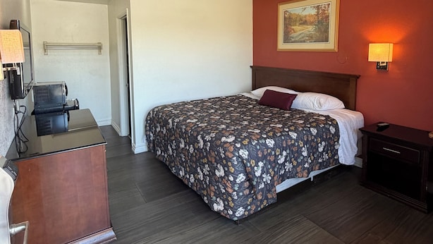 Een hotelkamer met een bed, bureau en een schilderij aan de muur.