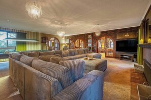 A living room with a large sectional sofa, a fireplace, and a television. - Southern Edge Retreat Vintage Charm by the Bay (Margate)