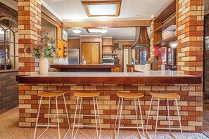 A kitchen with a brick wall, a central island with stools, and a visible sink. - Southern Edge Retreat Vintage Charm by the Bay (Margate)