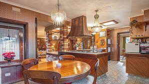 Eine geräumige Küche mit einer zentralen Kochinsel, einem Essbereich mit Holztisch und Stühlen sowie einer Bar mit Kühlschrank und Kaffeemaschine.