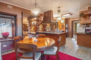 A spacious kitchen with a central island, a dining area with a wooden table and chairs, and a bar area with a refrigerator and coffee machine. - Southern Edge Retreat Vintage Charm by the Bay (Margate)