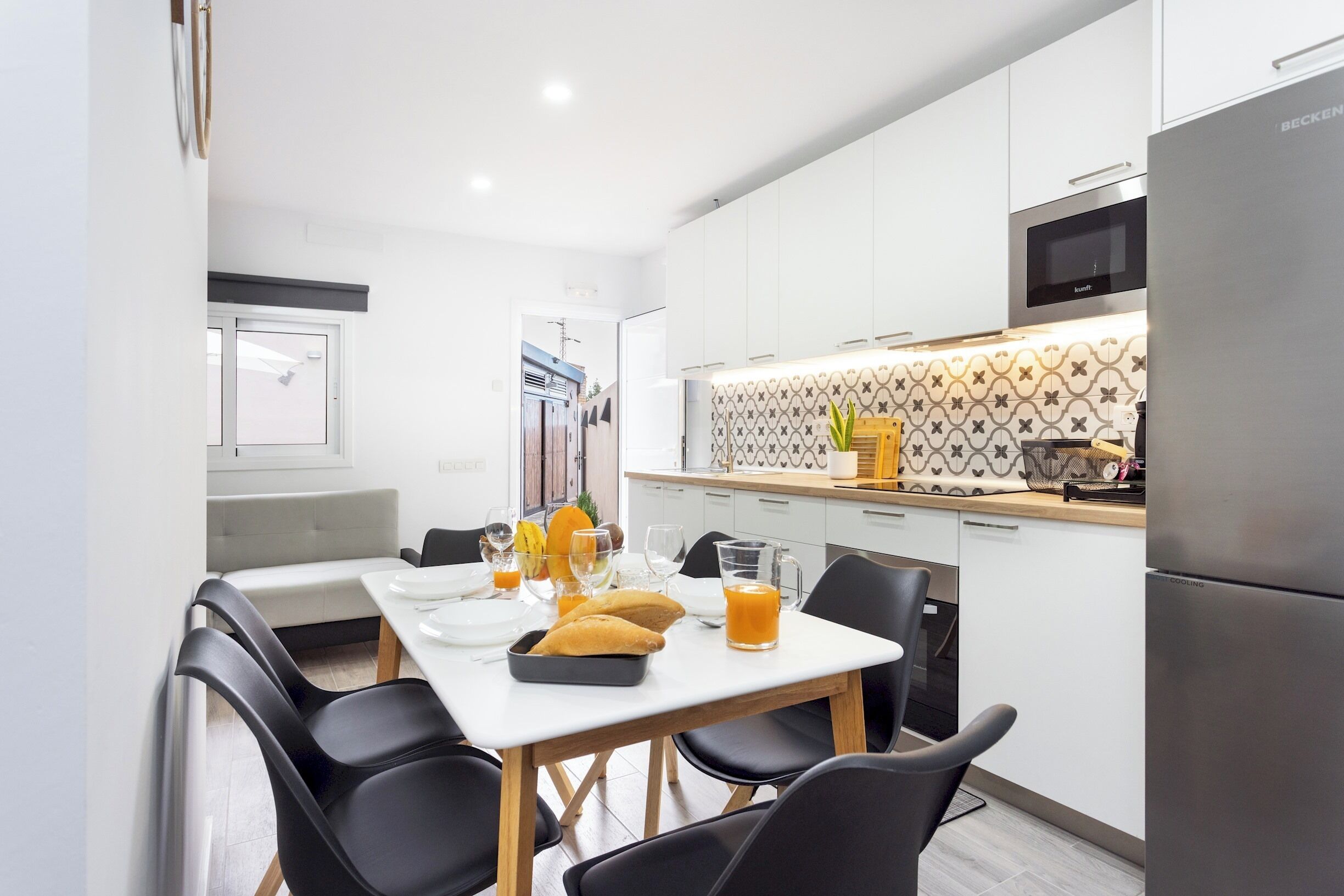 A modern kitchen with white cabinets, a microwave, and a stainless steel refrigerator.