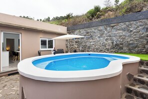 A swimming pool with a stone wall and a door leading to a patio area.