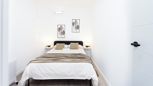 Ein Hotelzimmer mit Bett, Nachttischen, Wandbildern und einer Tür.