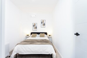 A hotel room with a bed, bedside tables, wall art, and a door. - TenoHomes Sunny Terrace & Private Pool (Icod de los Vinos)