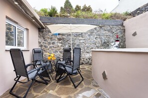 An outdoor patio with a stone wall, a table with chairs, and a bottle of wine. - TenoHomes Sunny Terrace & Private Pool (Icod de los Vinos)