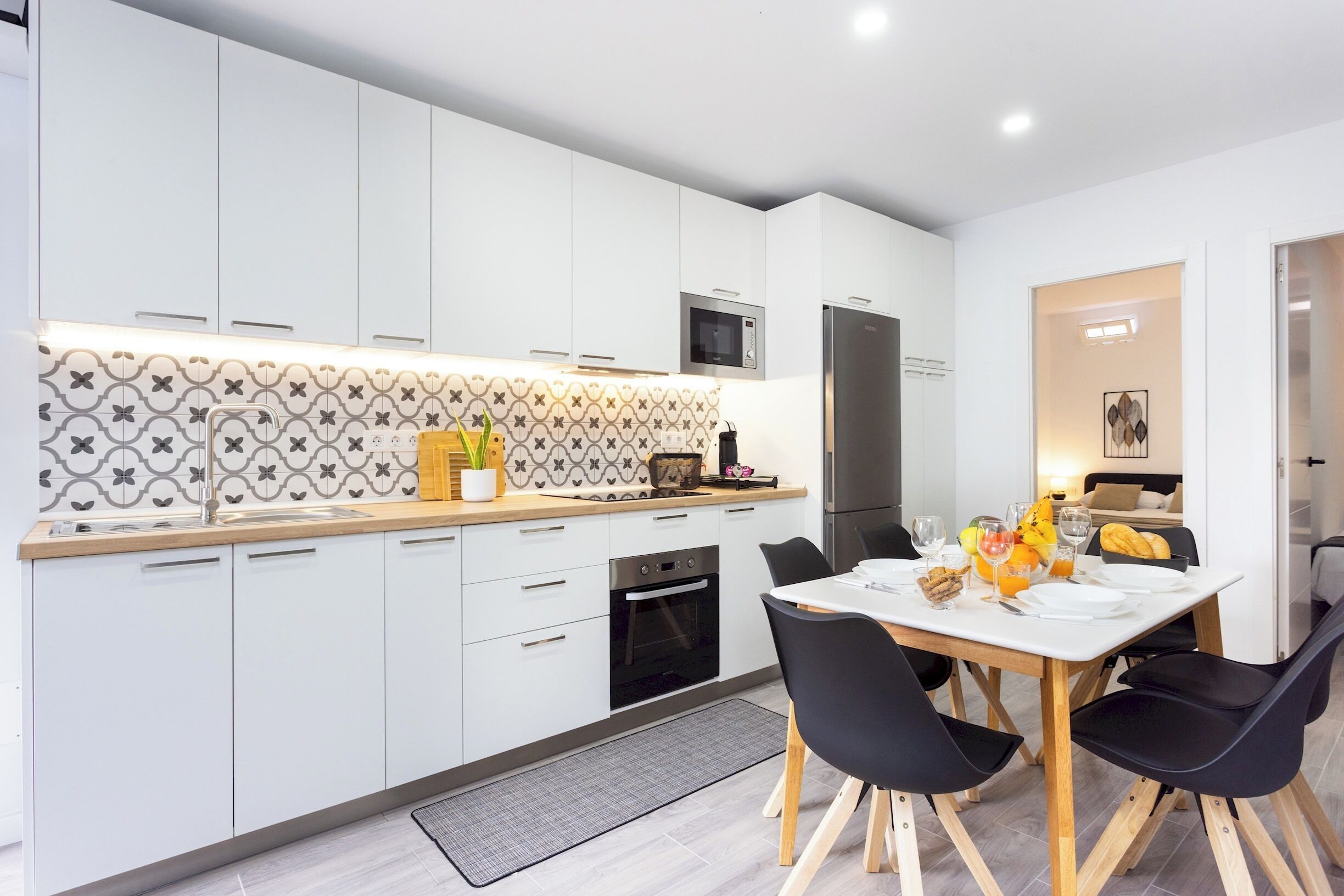 A modern kitchen with white cabinets, a microwave, and a built-in oven.