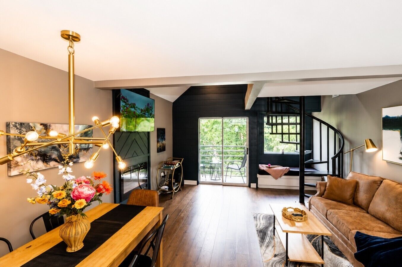 Un interior moderno con zona de comedor, sofá, escalera y vista a zonas verdes.