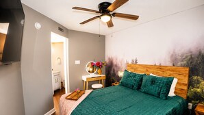 A bedroom with a bed, a vanity with a mirror, a ceiling fan, and a wall mural. - Heavenly Hideaway | Indoor Outdoor Pools- Hot Tubs- Private Balcony (Gatlinburg)