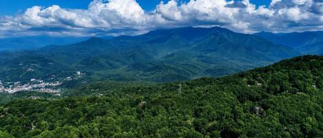 A mountainous landscape with dense forest and a clear sky.