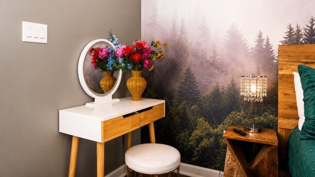 A bathroom with a vanity, a mirror, a stool, a wall-mounted lamp, and a green pillow. - Heavenly Hideaway | Indoor Outdoor Pools- Hot Tubs- Private Balcony (Gatlinburg)