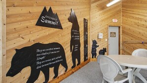 A wooden interior with a wall-mounted sign reading 'Gatlingburg Summit,' a bear silhouette, and a table with chairs. - Heavenly Hideaway | Indoor Outdoor Pools- Hot Tubs- Private Balcony (Gatlinburg)
