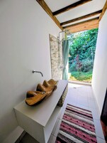 Un baño con lavamanos de madera, ducha y vistas a zonas verdes.