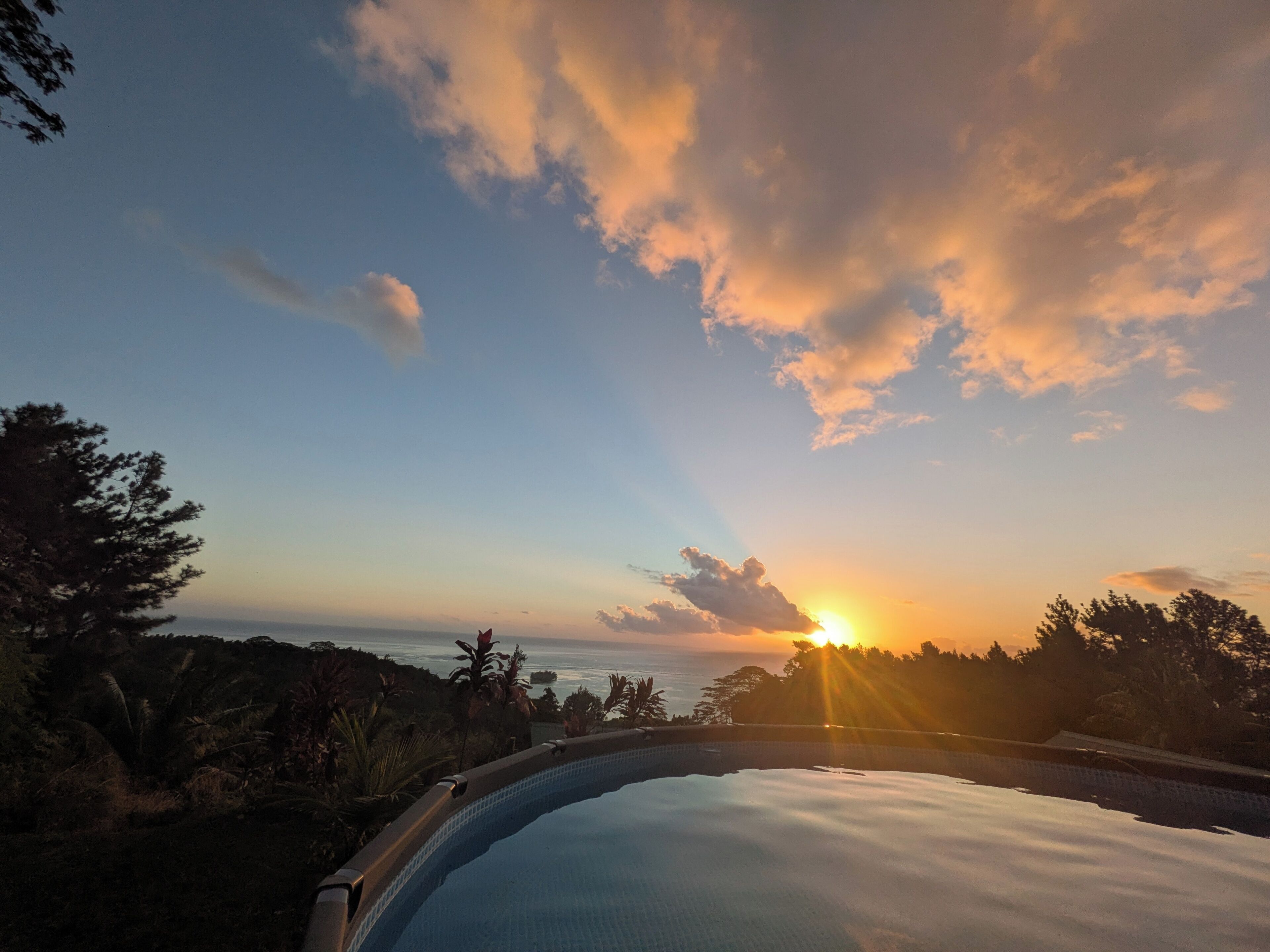 Una piscina con vistas a la puesta de sol sobre el océano.