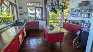Una cocina con vigas de madera, encimera roja y ollas colgantes.