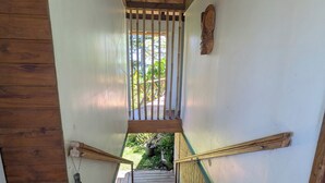 A wooden staircase with a metal railing, leading to an outdoor area with greenery. - Fare Tihi Moana (Tumaraa)