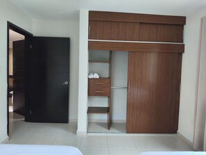 Ein Schlafzimmer mit einem Bett, einem Schrank mit vielen Fächern und einer Tür zu einem anderen Raum.