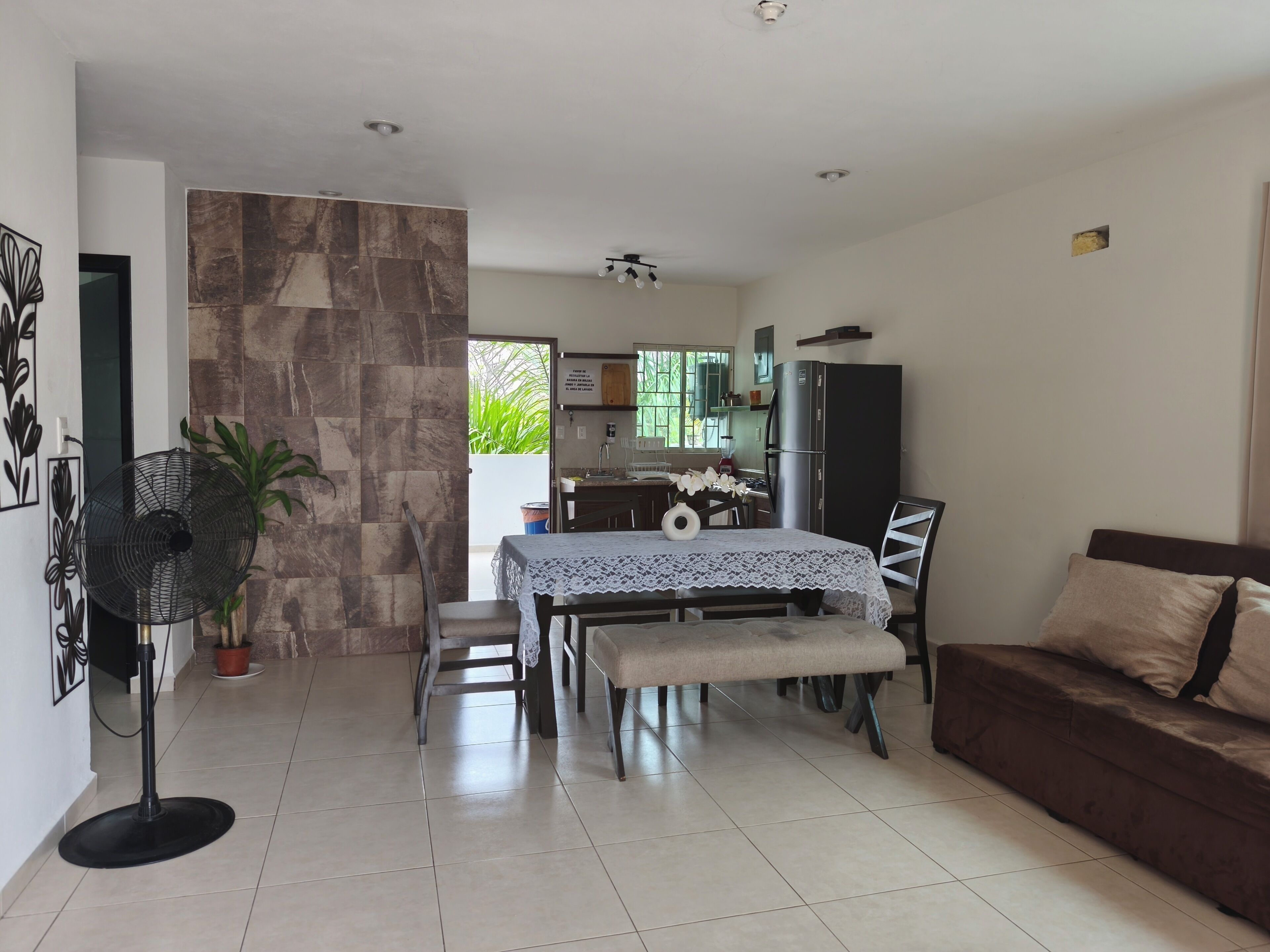 A modern living room with a dining area, kitchen, and a large window.