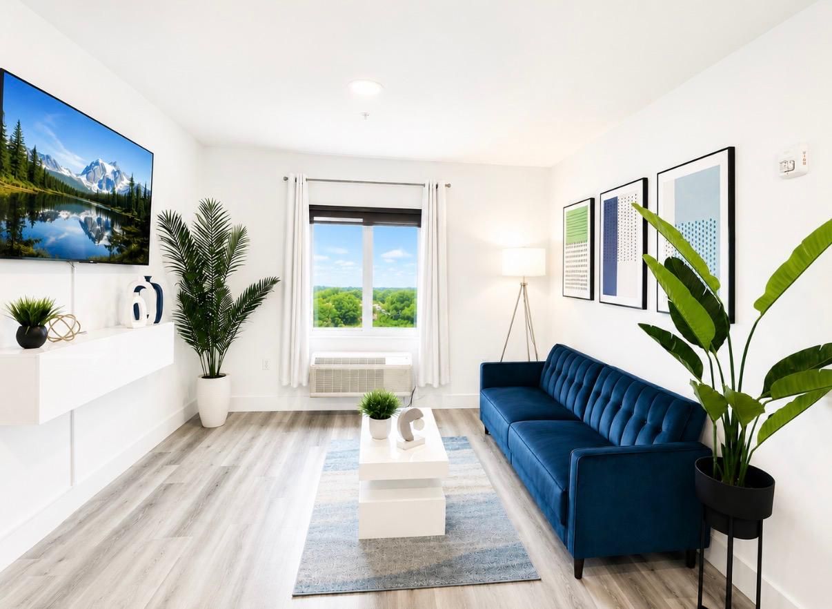 Una sala de estar moderna con un sofá azul, un televisor de pantalla plana y un ventanal con vistas a la vegetación.