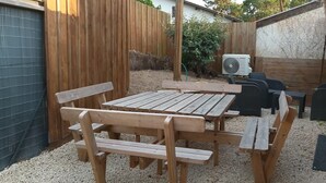 Eine Holzterrasse mit Tisch und Bänken, umgeben von einem Holzzaun und einem Garten.