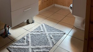Ein Badezimmer mit Holzeinrichtung, einem Waschbecken mit Spiegel, einem Handtuchhalter und einem Fenster.