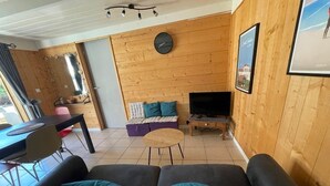 Ein Wohnzimmer mit einer Couch, einem Couchtisch, einem Fernseher und einer Holzwand.