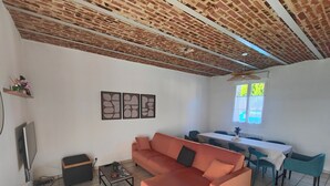 A living room with a sofa, a coffee table, a TV, and a dining area with a table and chairs. - La Clef des Vignes 3 (Roye)
