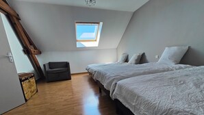 A bedroom with a loft-style ceiling, a skylight, a wooden floor, a sofa, and two beds. - La Clef des Vignes 3 (Roye)