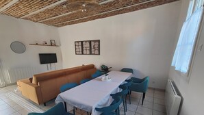 A dining area with a table, chairs, a sofa, a TV, and artwork on the wall. - La Clef des Vignes 3 (Roye)