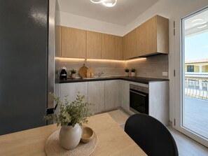 Eine moderne Küche mit Holzschränken, einer schwarzen Arbeitsplatte und einem eingebauten Ofen.